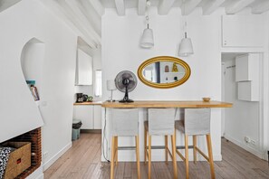 Eine moderne Küche mit einer Holztresen, zwei Barhocker, einem schwarzen Ventilator und einem goldfarben gerahmten Spiegel.