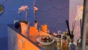 A modern bathroom with a hexagonal tile wall, a glass shower enclosure, and a vanity with toiletries. - Palmaria Sky Bubbles Room - Sleep Under the Stars in a Dream Bubble Room (Ponza)