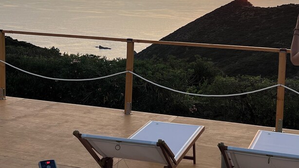 A hot tub with a view of the ocean at sunset, lounge chairs, and a wooden deck. - Palmaria Sky Bubbles Room - Sleep Under the Stars in a Dream Bubble Room (Ponza)