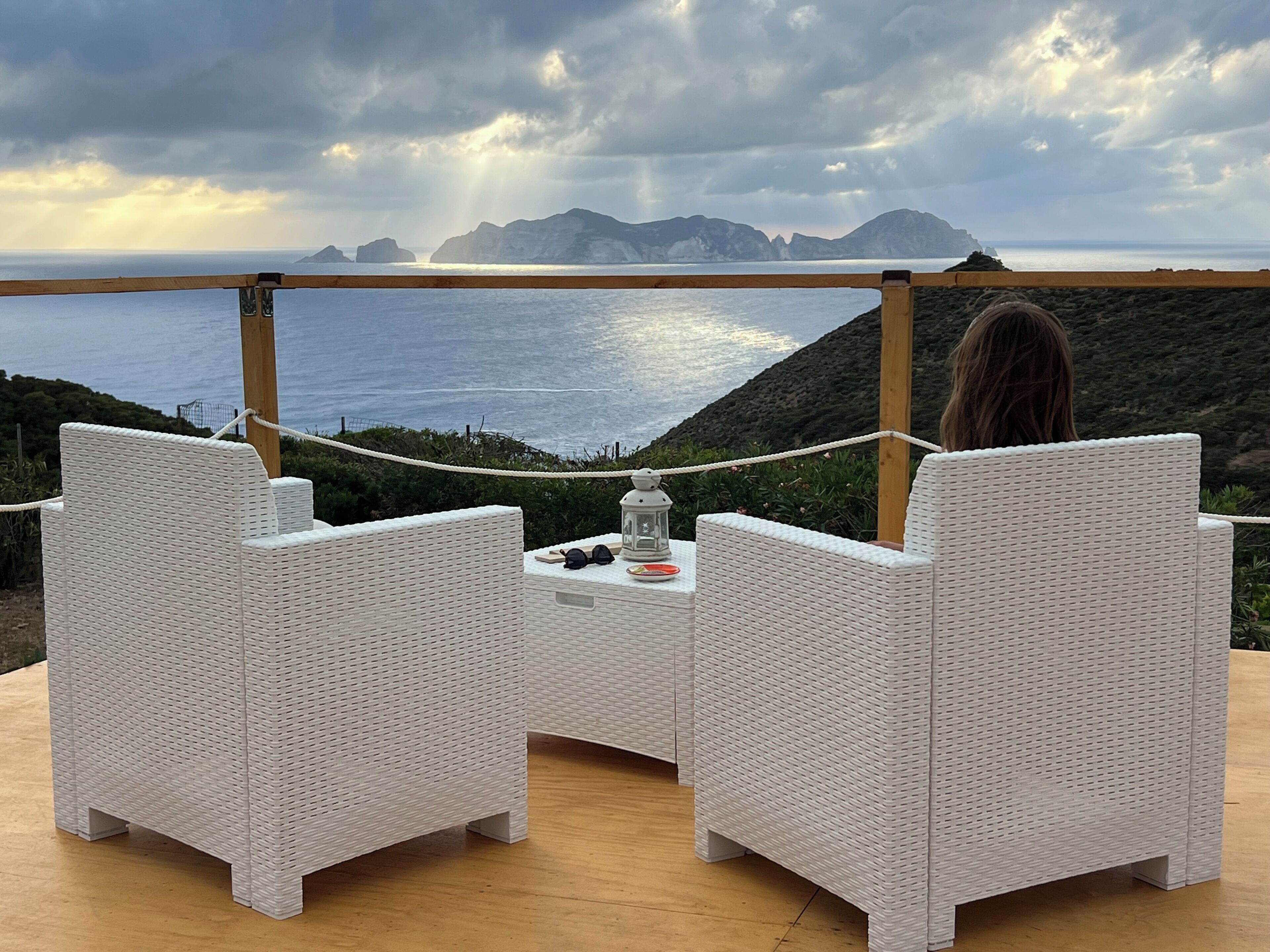 A terrace with wicker furniture overlooking a coastal view.