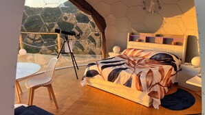 A bedroom with a large bed, a telescope, and a view of a mountainous landscape. - Palmaria Sky Bubbles Room - Sleep Under the Stars in a Dream Bubble Room (Ponza)