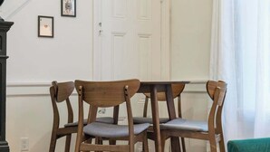 A dining area with a round table and four wooden chairs with grey cushions.
