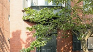 A brick building with a black door and steps leading to the entrance.