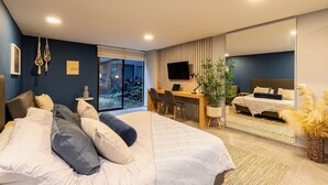 A modern bedroom with a large bed, a desk, and a large mirror. - Loft with garden view for natural relaxation (Medellín)