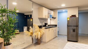 A modern kitchen with light wood cabinets, a stainless steel refrigerator, and a large mirror. - Loft with garden view for natural relaxation (Medellín)