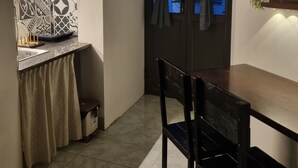 Cocina compacta con comedor, que incluye una mesa pequeña, sillas, un lavamanos y un ventanal con cortinas.