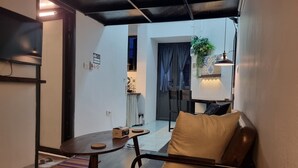 Una sala acogedora con un sofá, una mesita redonda y una planta colgante.