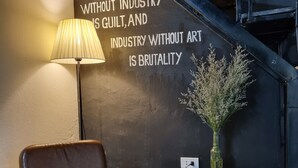 Una habitación con una butaca de cuero, una lámpara, una mesa de ladrillo y una frase motivacional en la pared.