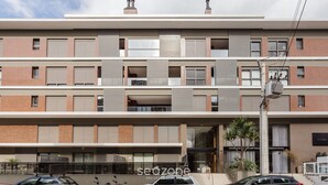 A multi-story building with a modern architectural design, featuring balconies, large windows, and a ground-level entrance with a sign. - Beautiful apt Less Than 5min From the Beach Vrn302 (Florianópolis)