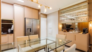 A modern kitchen with a glass dining table, stainless steel appliances, and a built-in wine rack.