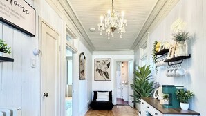 A hallway with a wooden herringbone floor, a chandelier, and a sign that reads "Home".