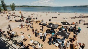A beachside restaurant with outdoor seating, tables, and umbrellas.