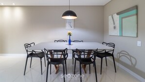 A modern dining area with a round table, black chairs, a blue vase with flowers, and a black pendant light.