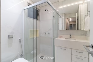 A modern bathroom with a glass-enclosed shower, a white sink, and a mirror above the vanity.