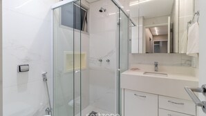 A modern bathroom with a glass-enclosed shower, a white sink, and a mirror above the vanity.