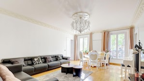 A modern living room with a grey sofa, two round coffee tables, and a chandelier.