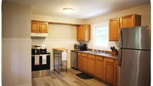 Una cocina con armarios de madera, electrodomésticos de acero inoxidable, microondas y refrigerador.