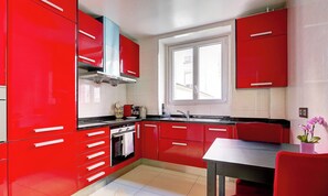 Eine moderne Küche mit roten Schränken, einem Fenster und einem Essbereich.
