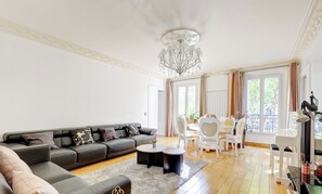 Ein modernes Wohnzimmer mit einem grauen Sofa, zwei runden Couchtischen und einer Deckenleuchte.