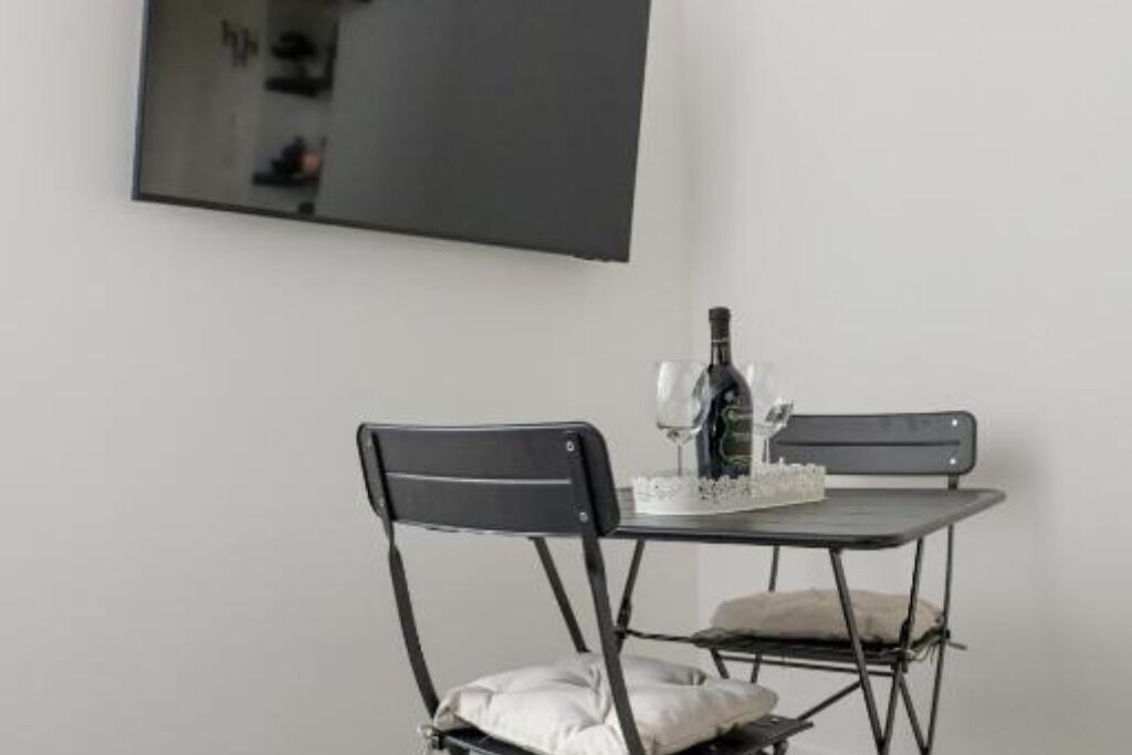 A compact room with a foldable table and two chairs, a bottle, and a small decorative item on the table.