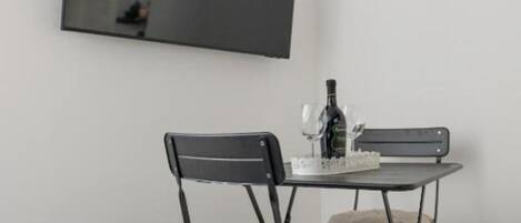 A compact room with a foldable table and two chairs, a bottle, and a small decorative item on the table.