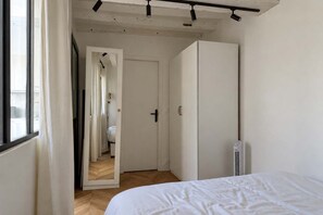 A bedroom with a bed, a wardrobe, a radiator, and a door leading to a bathroom. - Cocon parisien • Rue de la Verrerie (Paris)