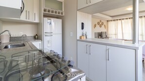 A modern kitchen with white cabinets, a built-in oven, and a stainless steel refrigerator. - Beautiful apt 3 Minutes From Jurere Beach Vma101 (Florianópolis)