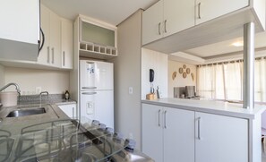 Eine moderne Küche mit weißen Schränken, einem eingebauten Backofen und einem Edelstahl-Kühlschrank.