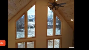 A room with large windows, a sloped ceiling, and a ceiling fan. - Modern 3BR/4BA Windham chalet w/ hot tub, views & mins to ski, bars, dining! (Windham)