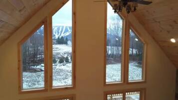 A room with a sloped ceiling, large windows, and a ceiling fan.