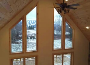 Una habitación con ventanas amplias, techo inclinado y ventilador de techo.