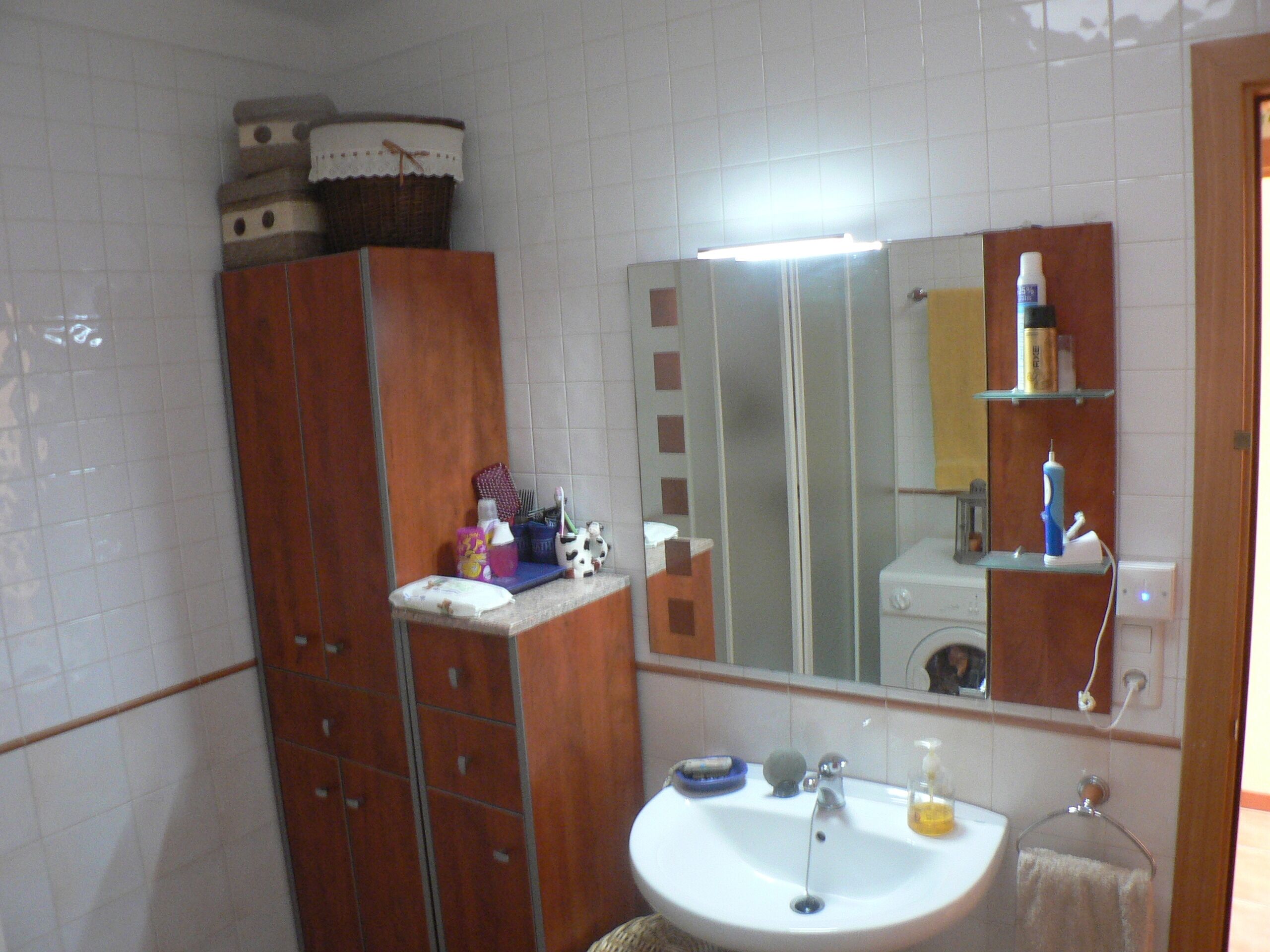 Een badkamer met een wastafel, spiegel en toiletartikelen.