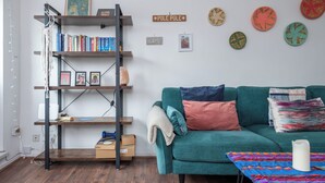 Una sala de estar con un sofá color turquesa, una estantería de escaleras de madera y platos decorativos en la pared.