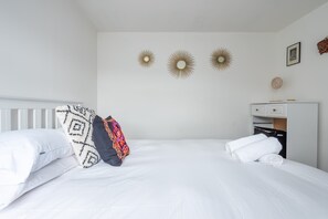 Una habitación de hotel con una cama blanca, un armario y tres adornos de sol en la pared.