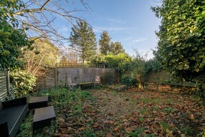 Un jardin avec une clôture en bois, un banc et une table.