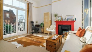 A living room with a fireplace, a sofa, a wooden chest, and a cowhide rug.