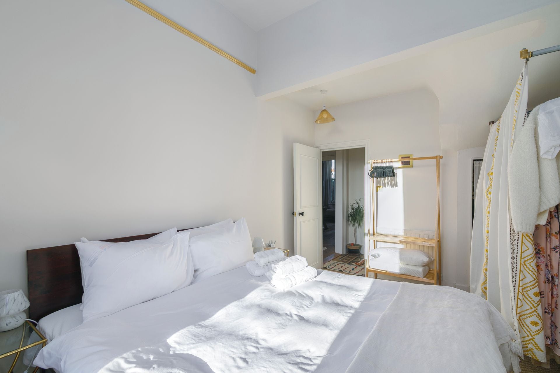 A hotel room with a large bed, a bedside table, a mirror, and a wardrobe.