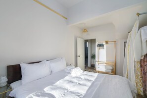 Une chambre d’hôtel avec un grand lit, une table de chevet, un miroir et une armoire.