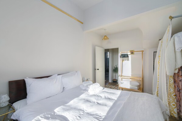 A hotel room with a large bed, a bedside table, a mirror, and a wardrobe.