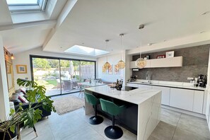 A modern kitchen with a large island, bar stools, and a view to a patio area.