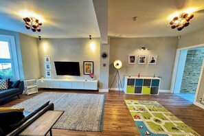 A modern living room with a flat-screen TV, a sofa, a coffee table, and a rug.