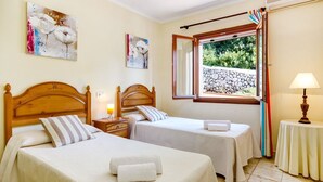 A hotel room with two beds, a window with a view of greenery, and artwork on the walls. - Villa Los Leones - Three Bedroom Villa, Sleeps 6 (Alayor)