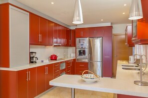 A modern kitchen with red cabinets, stainless steel appliances, and a white countertop. - Villa Bonita - Four Bedroom Villa, Sleeps 8 (Alayor)
