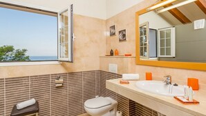A bathroom with a large window, a sink, a toilet, and a mirror.