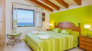 A bedroom with a bed, bedside tables, a window with a view, and a green wall.