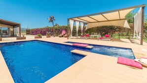 Una piscina con sillas de descanso y una pérgola.