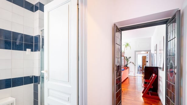 A hallway with a white door, a bench, and a staircase.