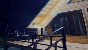 Et moderne loftrum med skrå vægge, store vinduer og en træterrasse med udesiddeplads.