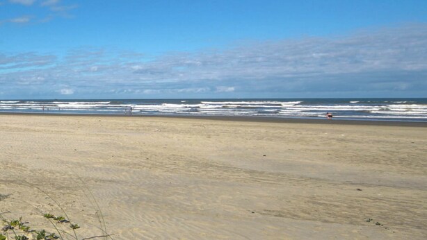 A wide sandy beach with gentle waves and a clear sky. - Casa Pet-friendly com Wi-fi e Churrasqueira (Itanhaém)