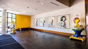 A lobby with a long reception desk, framed artwork on the wall, and a statue on the right.
